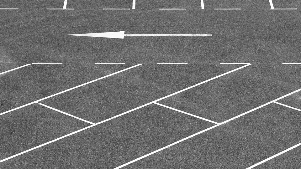 An empty asphalt parking lot marked with fresh white striping and a directional arrow